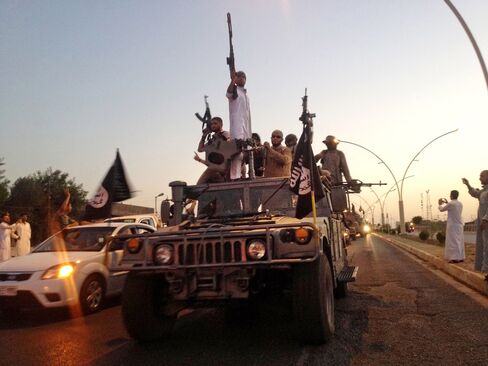 FILE - In this photo taken Monday, June 23, 2014, fighters from the Islamic State group parade in a commandeered Iraqi security forces armored vehicle down a main road at the northern city of Mosul, Iraq. An independent monitoring group says some bombings carried out by the U.S.-led coalition targeting the Islamic State group likely have killed hundreds of civilians. The coalition had no immediate comment on the report released Monday, Aug. 3, 2015. (AP Photo, File)