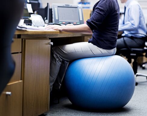 Woman in office sitting on an exercise ball | location: Cape Town, South Africa | description: Woman in office sitting on an exercise ball | location: Cape Town, South Africa