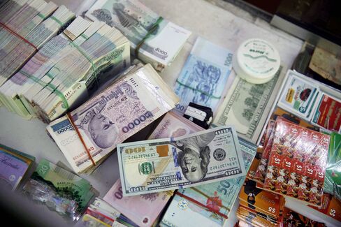 A U.S. one-hundred dollar banknote sits beside a stack of Cambodian riel banknotes at a currency exchange counter at Central Market in Phnom Penh.