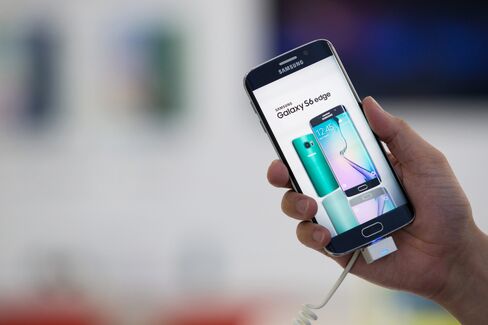 An employee holds a Samsung Galaxy S6 Edge smartphone at the company's showroom in Seoul, South Korea. Photographer: SeongJoon Cho/Bloomberg