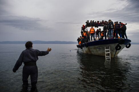 A Greek man greets migrants as they arrive on Lesbos