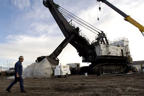 A worker walks past a coal shovel at a mine near Wright, Wyo.