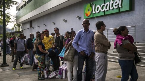 Shoppers wait in line outside of a pharmacy that had just received a shipment of diapers, in Caracas, on Feb. 18, 2015. Photographer: Meridith Kohut/Bloomberg