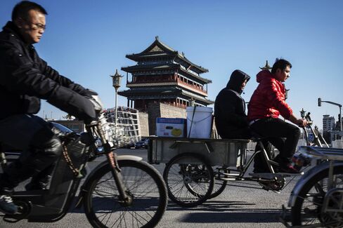 People ride a tricycle and electric bikes past the Zhengyangmen gate in Beijing, China, on Wednesday, Dec. 2, 2015. China's great rebalancing -- the long-sought shift away from investment and manufacturing towards consumption and services -- is one of the nation's big themes of the year. One problem: the rebalancing stops at the water's edge. Photographer: Qilai Shen/Bloomberg