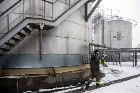 An employee carries a wrench as he walks beside an oil storage tank at an oil plant operated by Moravske Naftove Doly (MND) AS in Damborice, Czech Republic, on Friday, Jan. 8, 2016. Oil capped the biggest two-year loss on record in 2015 as the Organization of Petroleum Exporting Countries effectively abandoned output limits amid a global glut. Photographer: Martin Divisek/Bloomberg