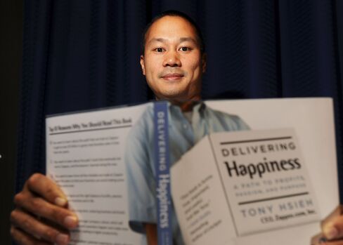 Zappos founder Tony Hsieh displays a copy of his autobiography Delivering Happiness.
