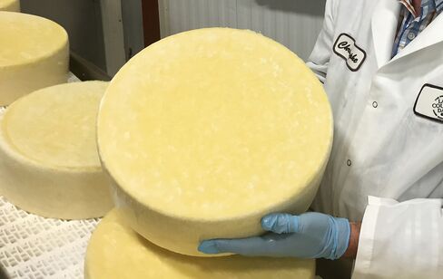 A cheese maker for Arthur Schuman Inc. holds a round of cheese in Turtle Lake, Wisconsin.