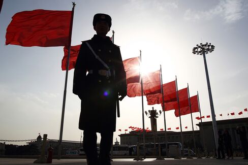 A paramilitary police officer stands guard in front of red flags at Tiananmen Square in Beijing, China.