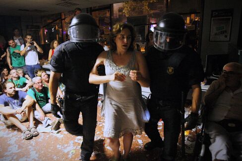 Colau (center) is carried out by police officers after occupying a bank in a protest to support a neighbor facing eviction in Barcelona on July 26, 2013.