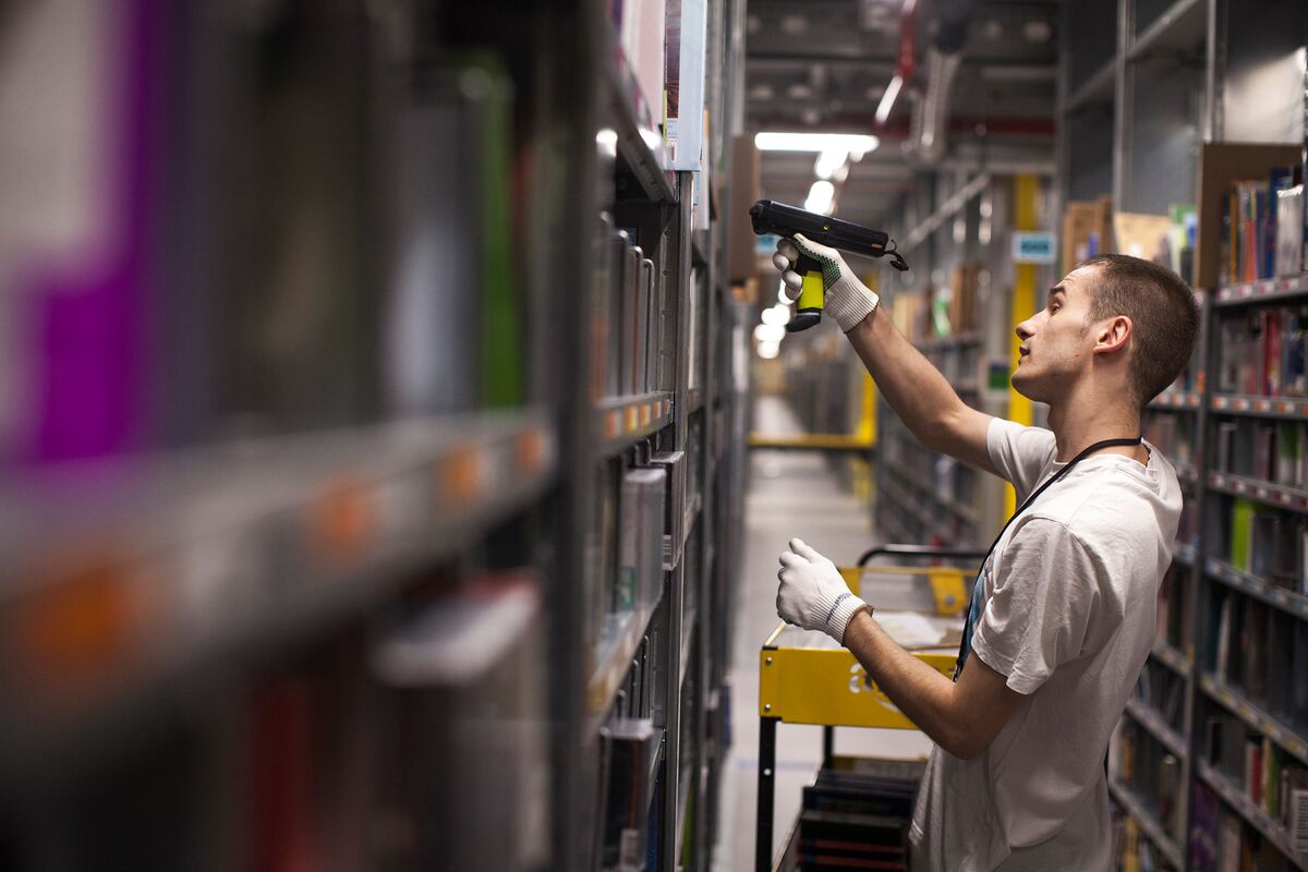 Amazon warehouse workers wear GPS tracking devices and are assigned products for collection by a hand-held scanner