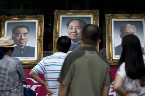 People look at portraits of former Chinese leaders Zhou Enlai, left, Mao Zedong, center, and Liu Shaoqi displayed in a shop on Wangfujing Street in Beijing, China, on Tuesday, Sept. 9, 2014.