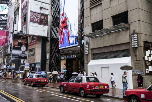 Shoppers and pedestrians walk past a Burberry Group Plc store, center, and a shuttered store vacated by Tag Heuer International SA on Russell Street in Hong Kong. Photographer: Xaume Olleros/Bloomberg