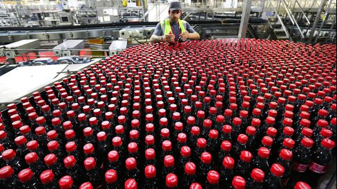 An employee inspects bottles at Coca-Cola Enterprises Ltd.'s bottling plant in Sidcup, U.K.
