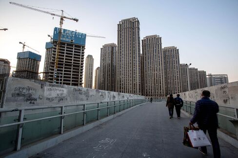 People walk on a overpass beside a huge construction site.