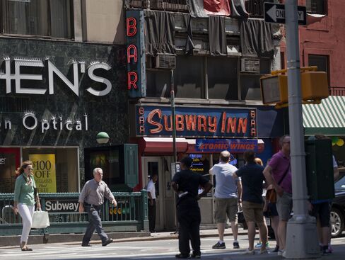 Pedestrians pass the Subway Inn bar in New York on July 25, 2014.  Photographer: Michael Nagle/Bloomberg