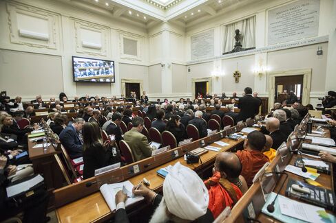 The Pontifical Academy of Sciences is a Vatican agency that has origins in Galileo’s time. It’s made up of 80 of the world’s top scientists, who keep the Bishop of Rome and the Vatican up to speed on new scientific research. On April 28, the academy hosted a conference on climate change and poverty. The religious leaders are seated to the right. The scientists face them, across the room. At the central podium, beneath the bust of Pope John Paul II, United Nations Secretary-General Ban Ki-moon delivers his address. They met in the great hall of the Vatican’s Casina Pio IV. The inscription on either side of the bust extols Pope John Paul II’s 1992 apology to Galileo.