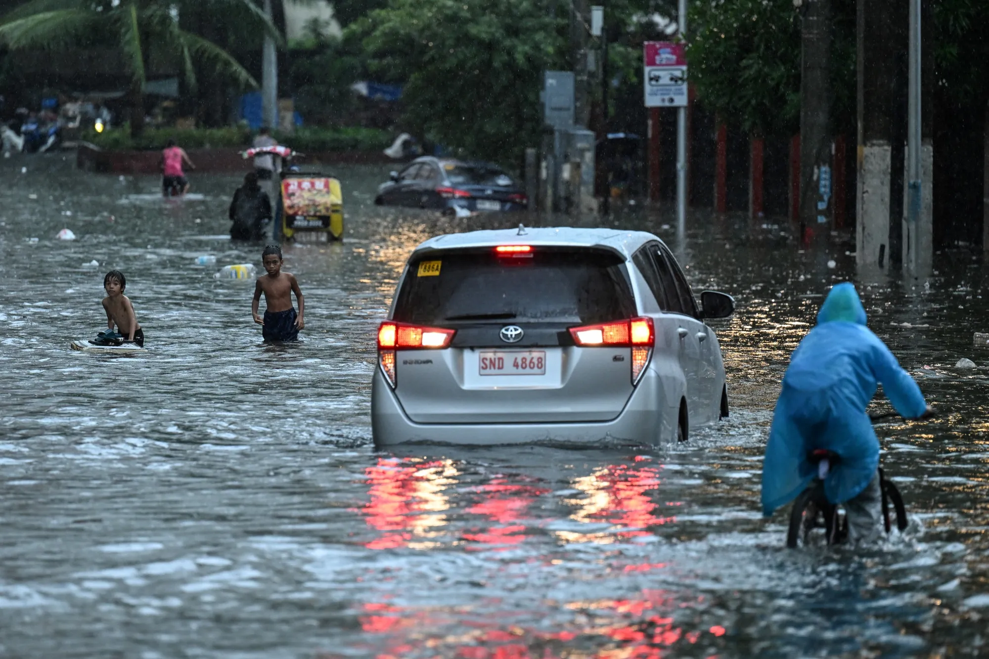 Vehicles plough through a flooded street in Manila on July 22.