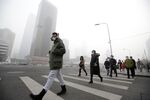 A man wearing a respirator walks toward an office building amid smog in Beijing.