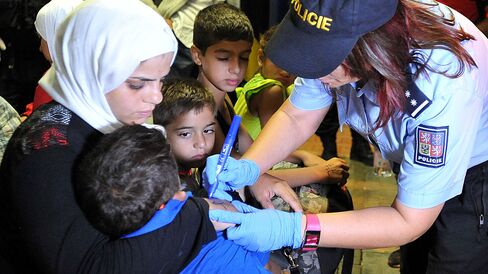 A Czech police officer marks a refugee with a number while detaining more than 200 refugees, mostly from Syria, on trains from Hungary and Austria at the railway station in Breclav, Czech Republic, on Sept. 1, 2015.