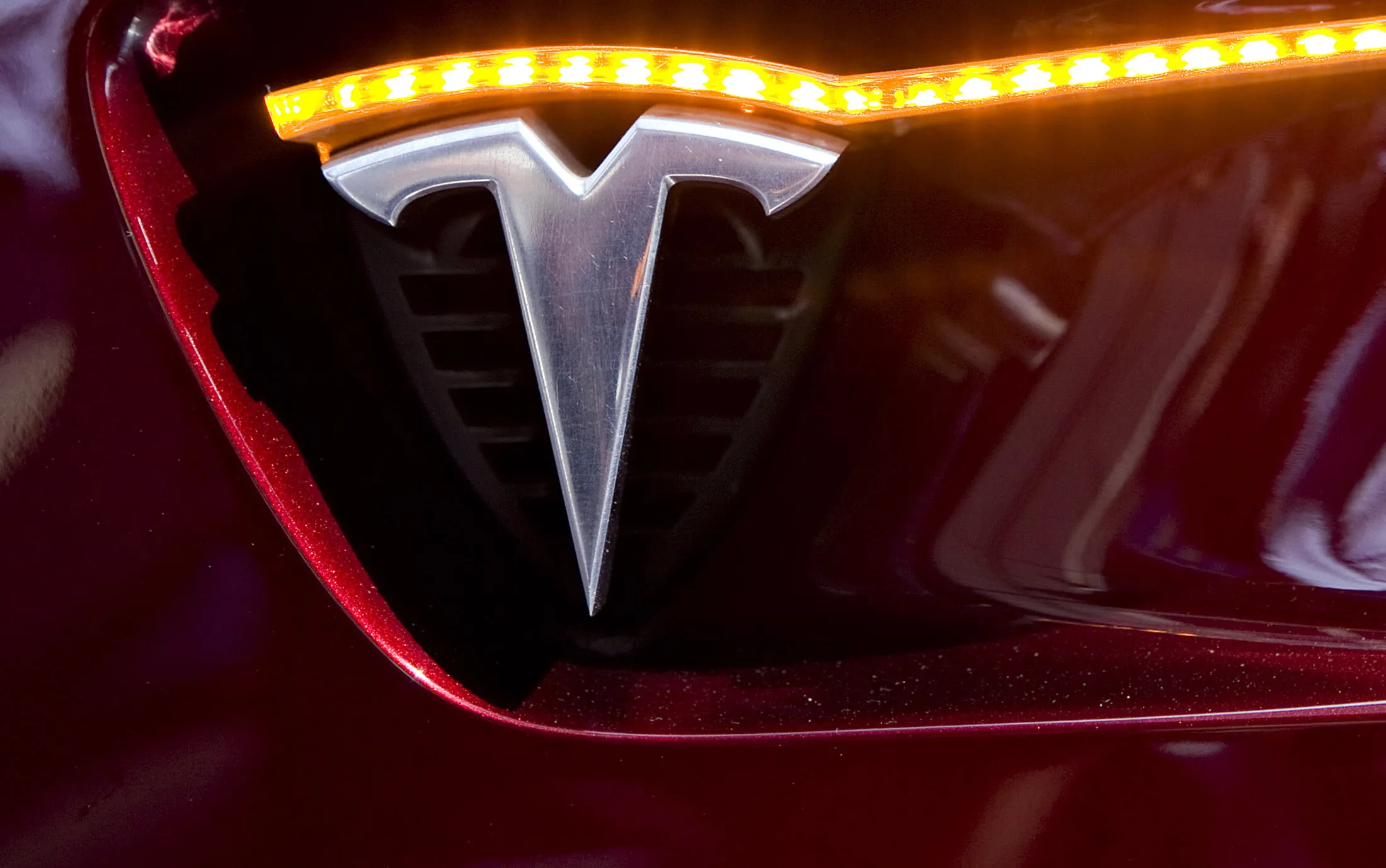 A Tesla Motors logo appears on the side of a Tesla Model S.
