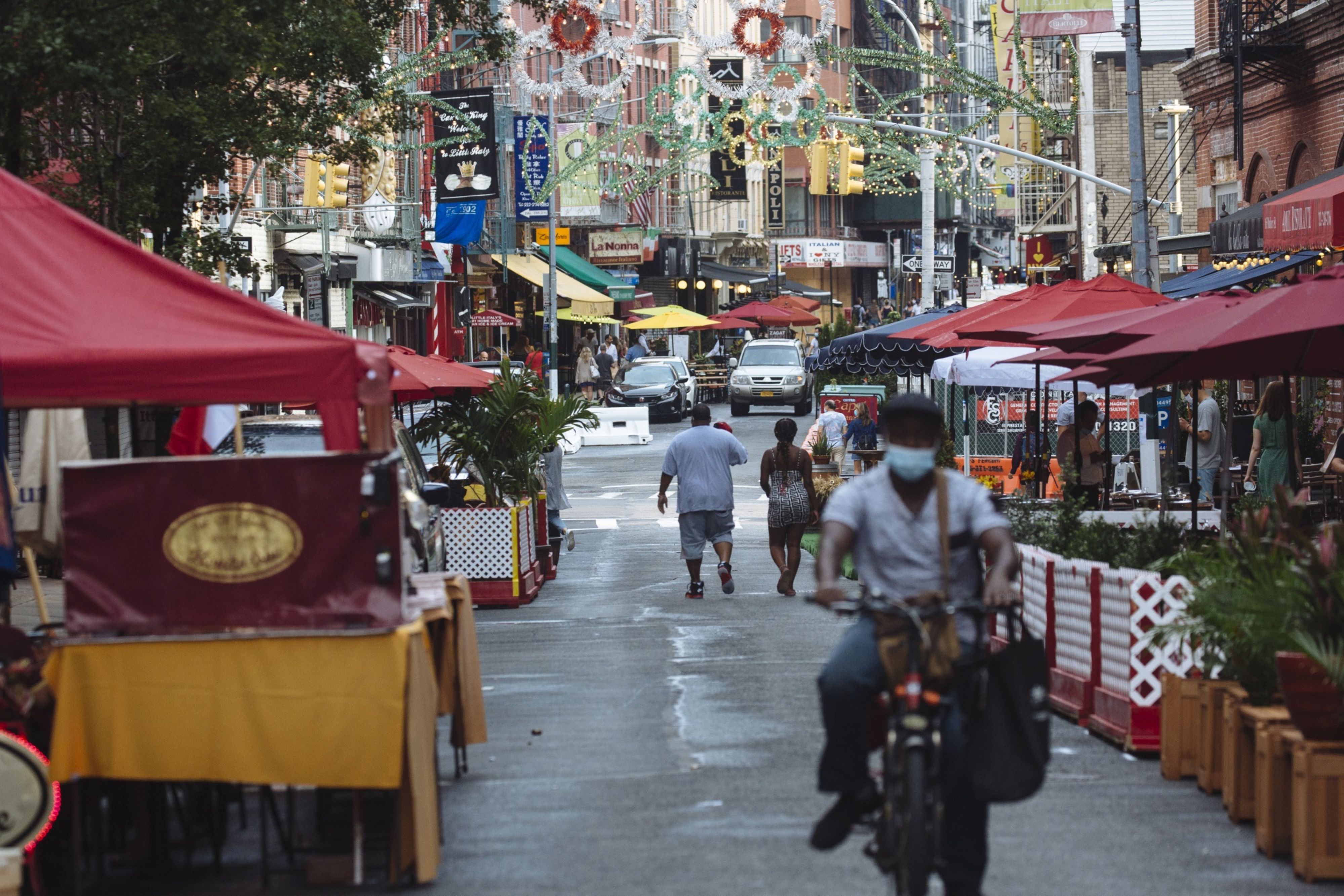 People walk down a street lined with outdoor seating for restaurants in the Little Italy neighborhood of New York in July 2020.&nbsp;