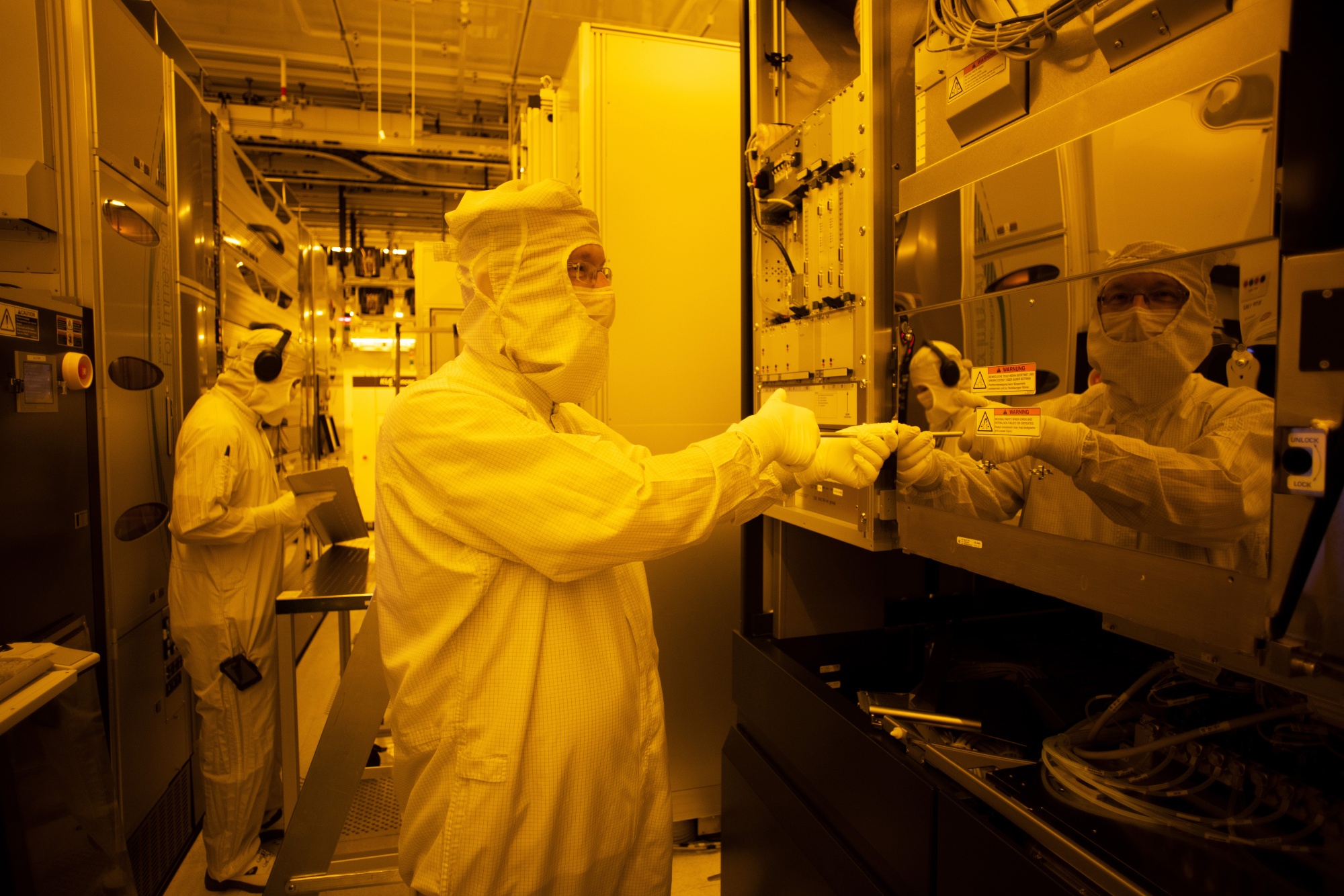 Employees work on production control in the clean room at a semiconductor fabrication plant in Dresden, Germany.