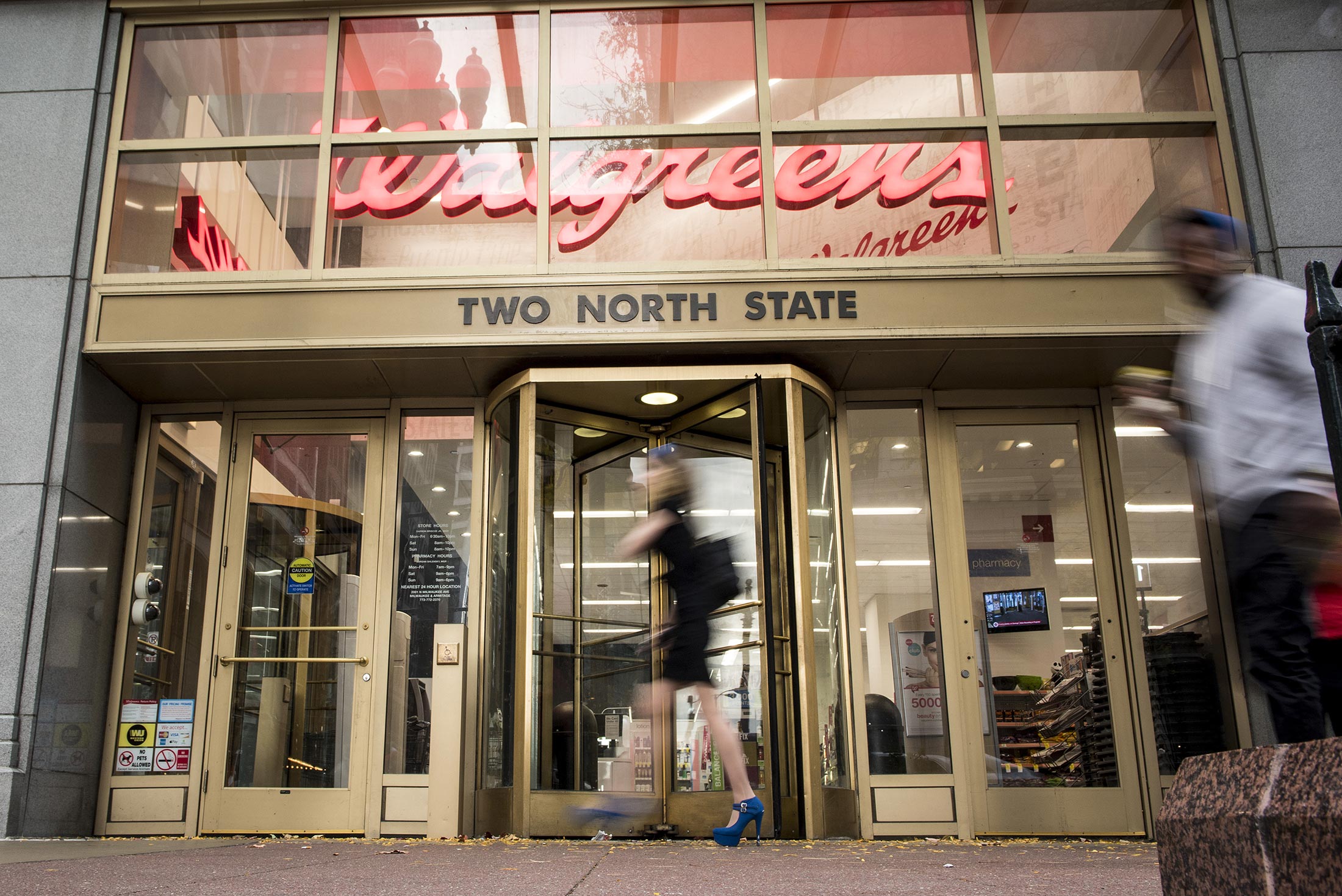 Pedestrians pass in front of a Walgreens Boots Alliance Inc. store in downtown Chicago, Illinois, U.S., on Tuesday, Oct. 18, 2016.
