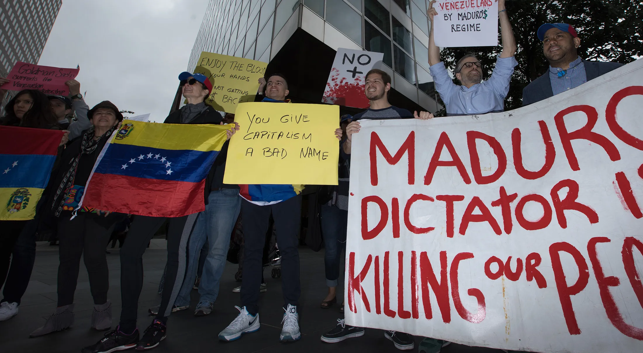 Demonstrators hold signs and Venezuelan flags during a protest outside of the Goldman Sachs Group Inc. headquarters in New York, on May 30, 2017.
