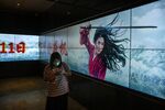 A Chinese woman walks by a screen displaying the trailer for the Disney film Mulan showing Chinese-American actress Liu Yifei on September 11, 2020 at a cinema in Beijing, China.