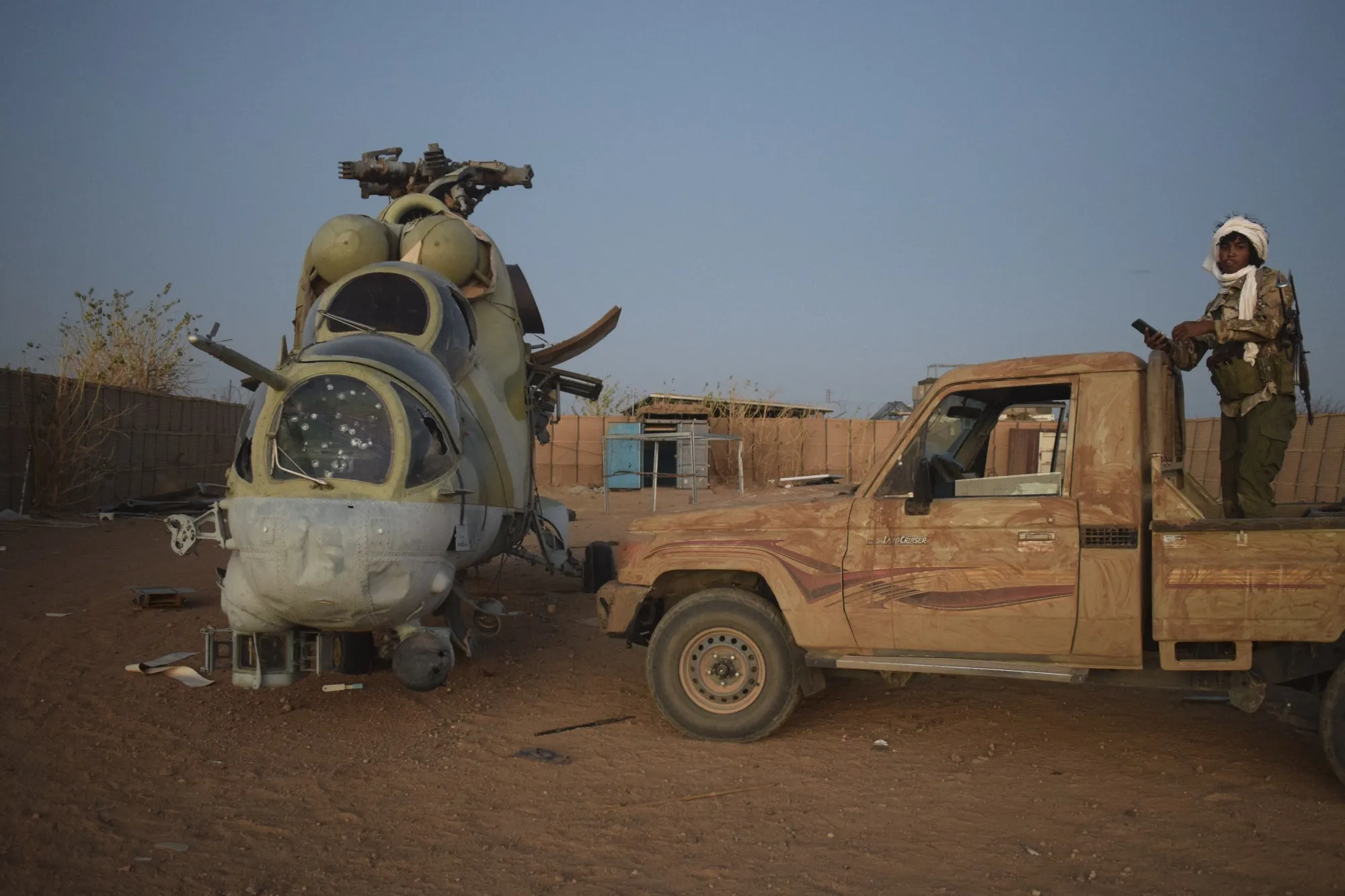 A&nbsp;soldier stands&nbsp;next to a damaged Mi-24 helicopter at the former Africa Corps barracks at Camp 2 in Kidal on May 6,.