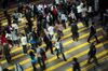 Pedestrians cross a road in the Central district of Hong Kong, China.