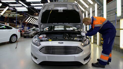 An employee performs a quality control inspection of a new Ford Focus