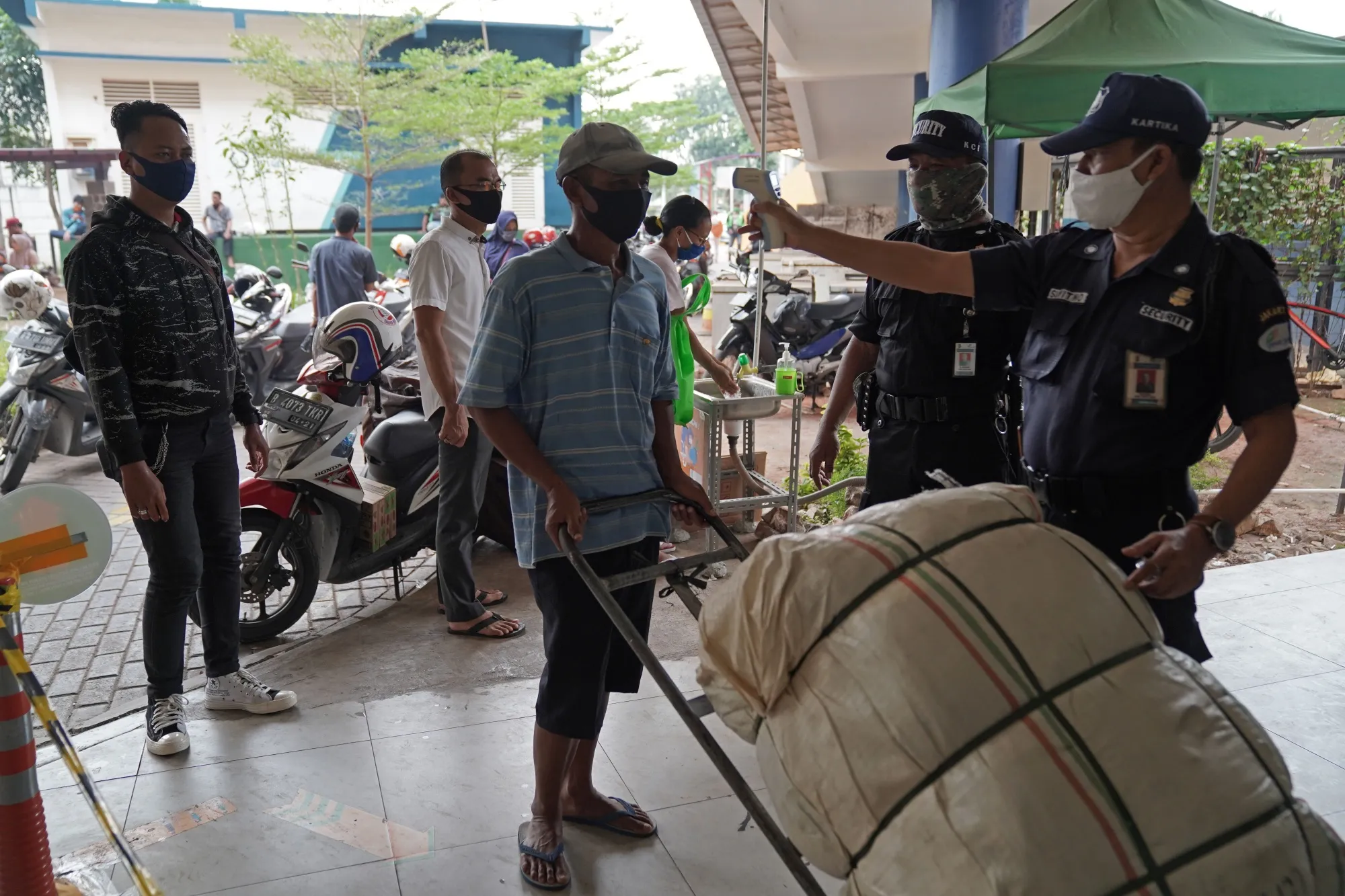 A security guard checks the temperature of a worker before entering the Pasar Senen market in Jakarta, Indonesia, on&nbsp;July 8, 2020.&nbsp;