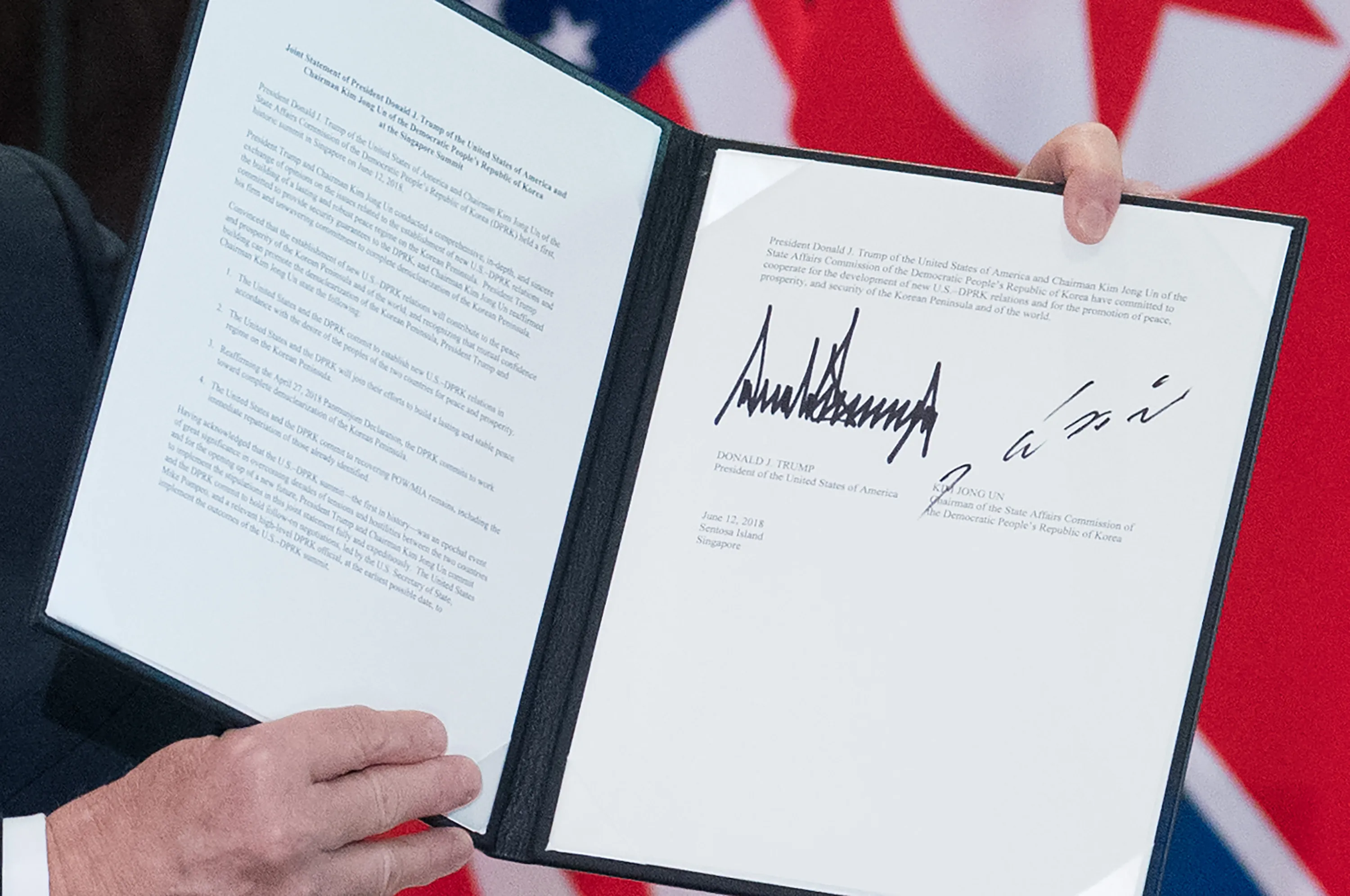 Trump holds up a document signed by him and Kim Jong Un.