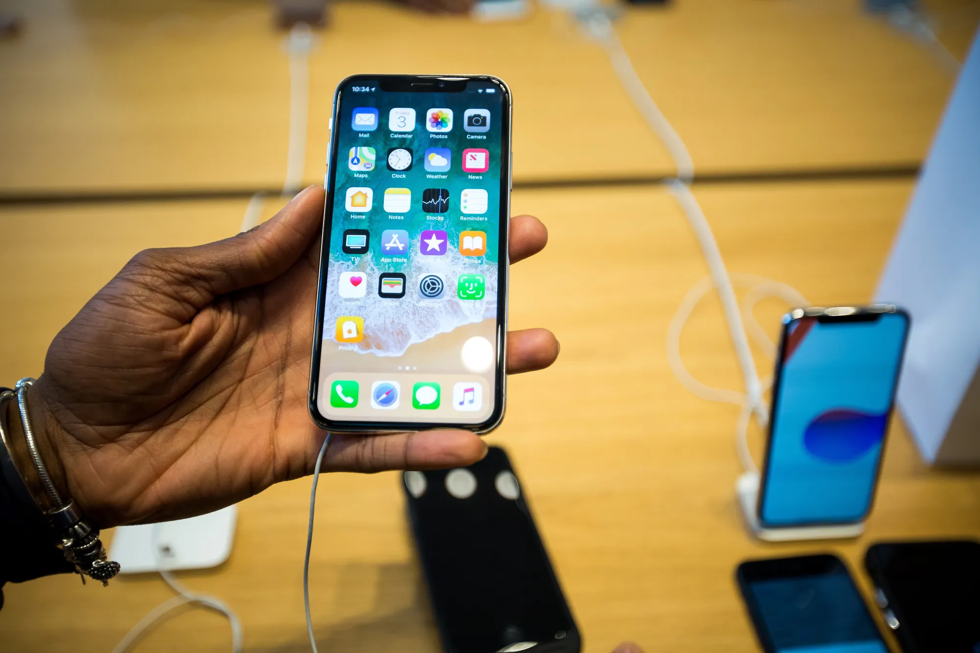 An employee holds an iPhone X smartphone while assisting a customer during the sales launch at a store in New York, U.S., on Friday, Nov. 3, 2017.