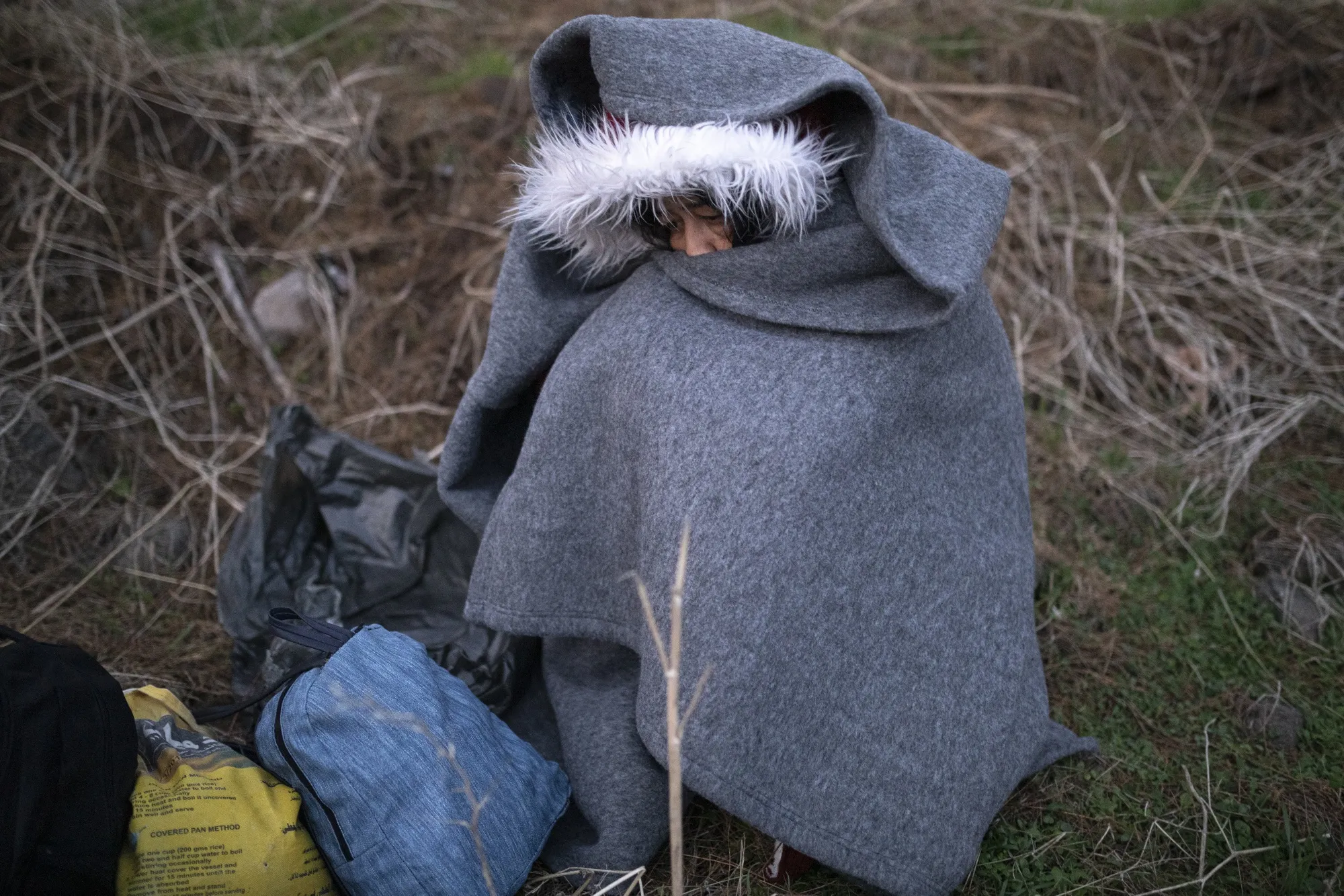 A migrant from Afghanistan huddles in a blanket after arriving by boat on the shoreline near the village of Skala Sikamineas, in Lesbos, Greece, on&nbsp;March. 1.