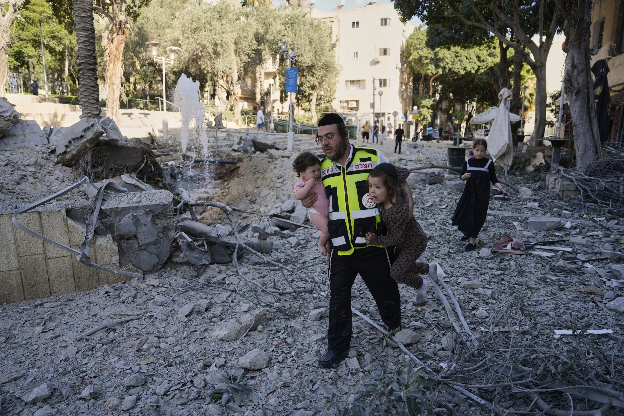 A rescue worker evacuates two children from the site where a missile launched from Iran struck Haifa, Israel on June 22.