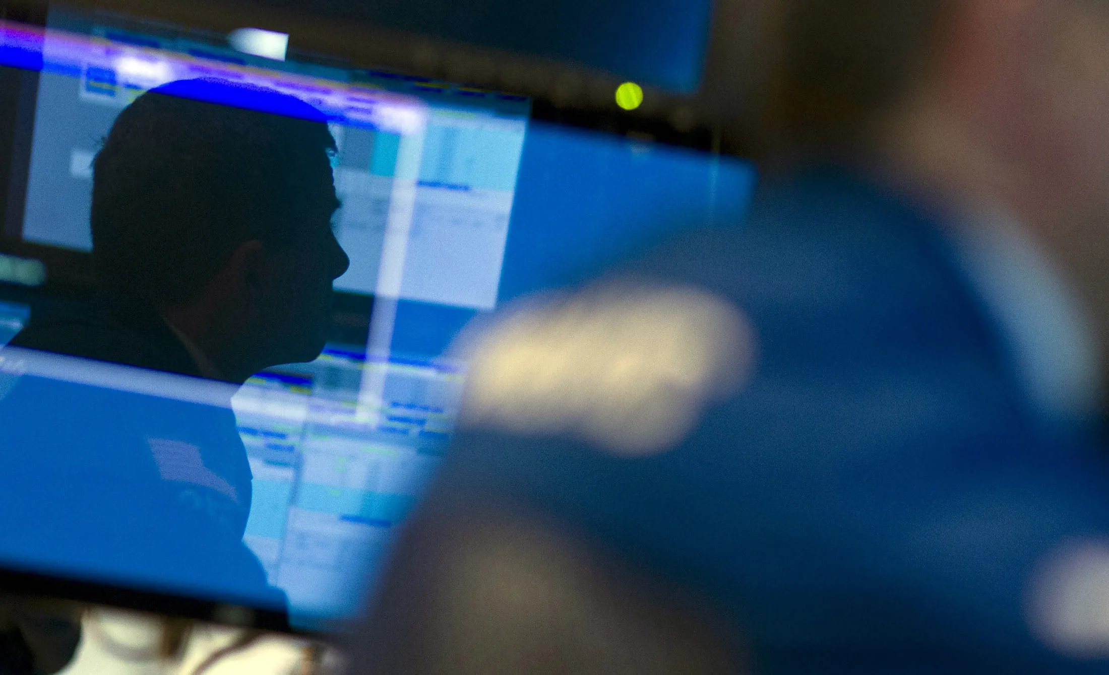 A trader is reflected in a monitor as he works on the floor of the New York Stock Exchange.
