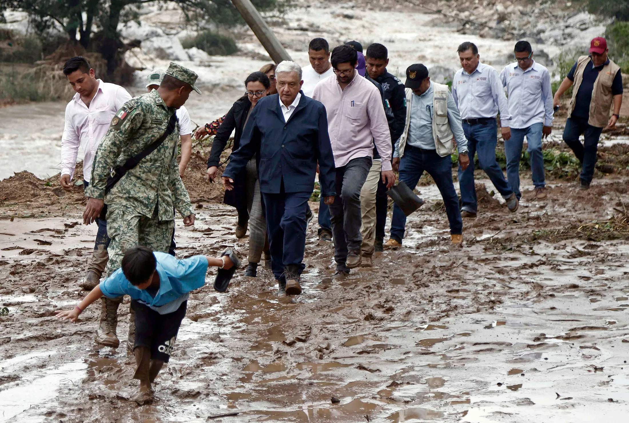President Lopez Obrador walks through mud during a visit near Acapulco, Guerrero State, Mexico, after the passage of Hurricane Otis, on Oct. 25.