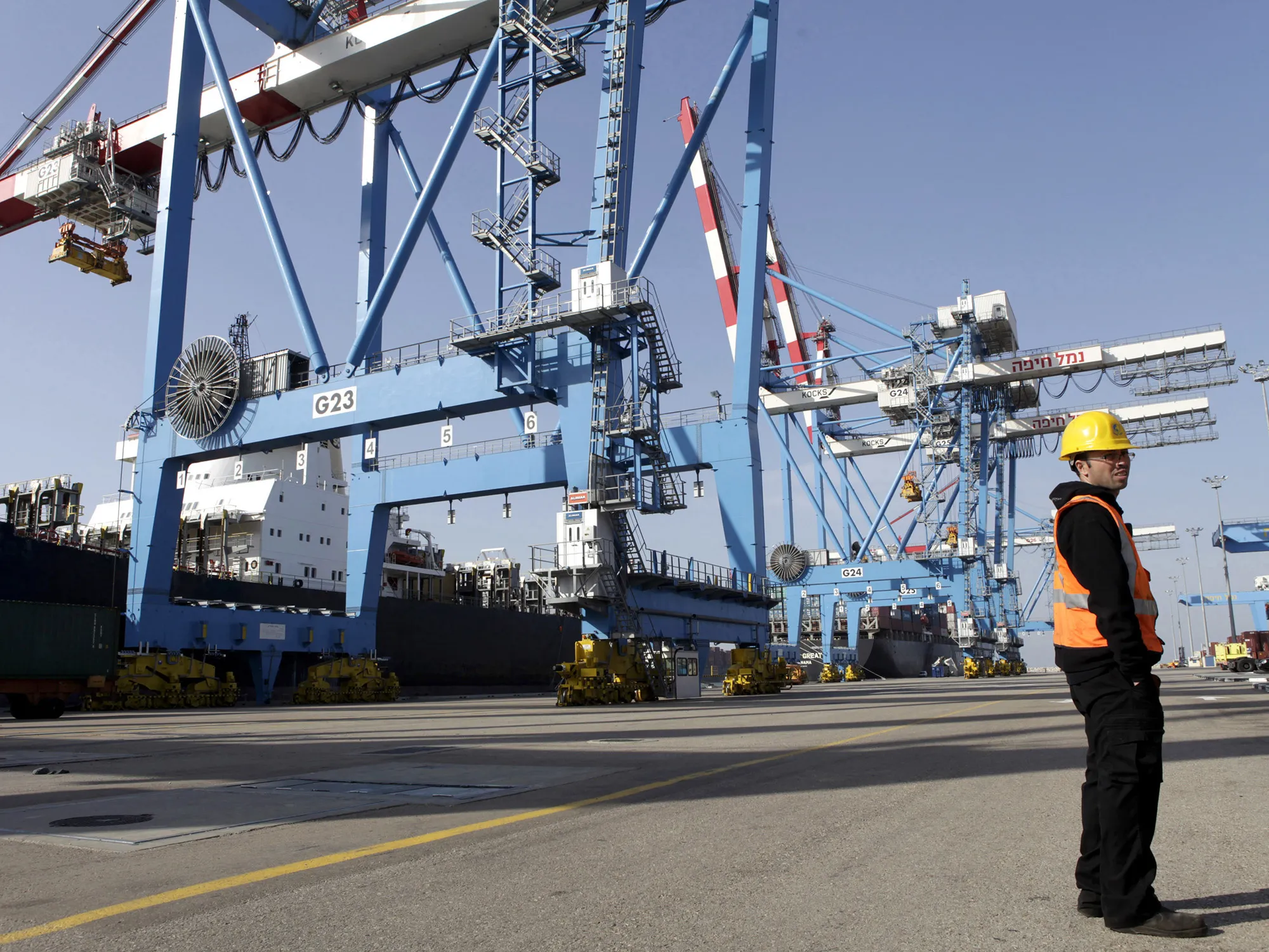 A port worker stands on the quay side near cranes at the Port of Haifa in Haifa, Israel.