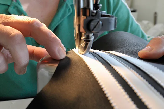 An employee attaches the three Adidas stripes to a leather soccer shoe at the company's factory in Scheinfeld, Germany.