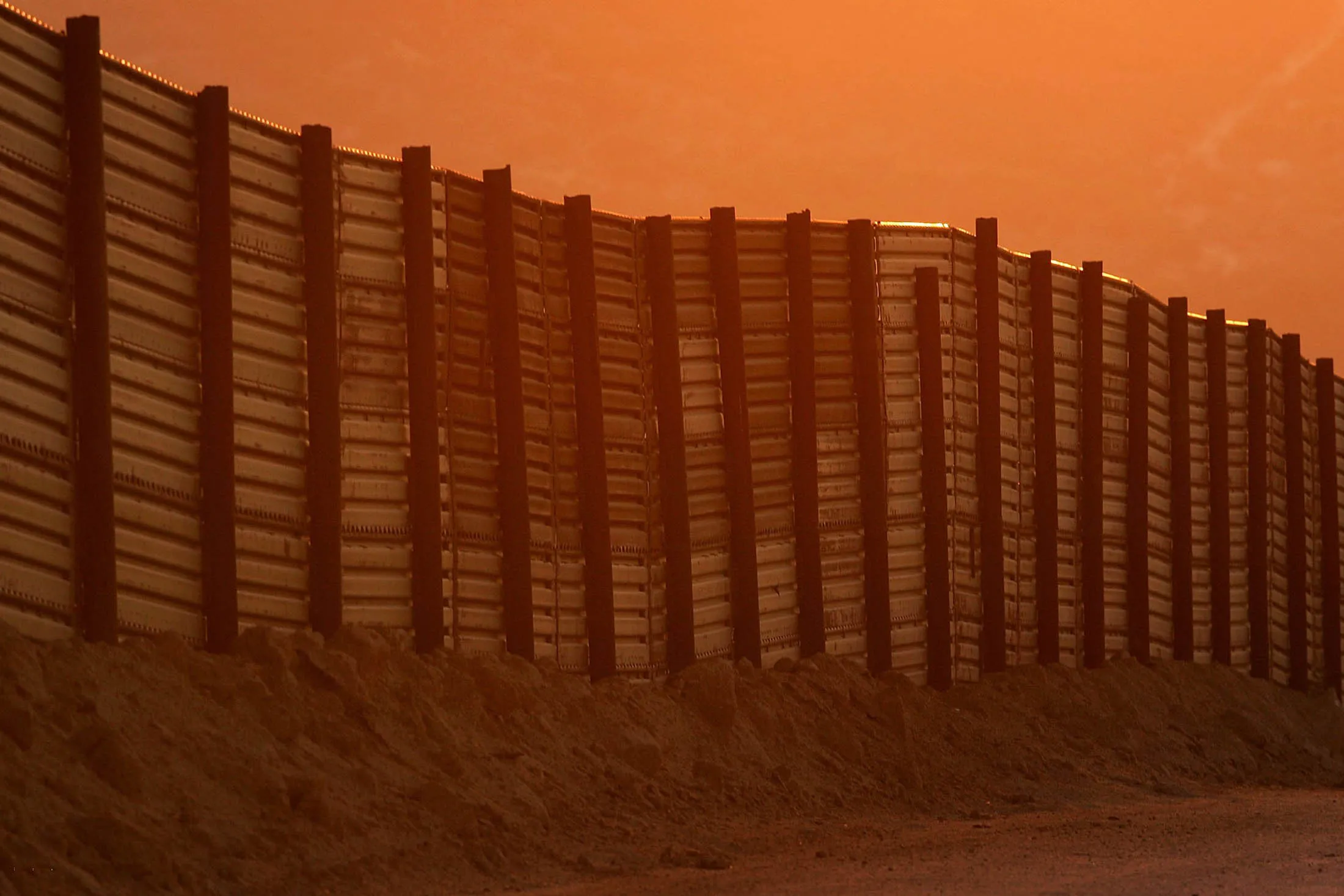 CAMPO, CA - OCTOBER 08: Dusk falls over a section of the US-Mexico border fence which activists opposing illegal immigration hope will be turned into a fully-lit double-fenced barrier between the US (foreground) and Mexico October 8, 2006 near Campo, California. US Fish and Wildlife Service wardens and environmentalists warn that a proposed plan by US lawmakers to construct 700 miles of double fencing along the 2,000-mile US-Mexico border, in an attempt to wall-out illegal immigrants, would also harm rare wildlife. Wildlife experts say cactus-pollinating insects would fly around fence lights, birds that migrate by starlight in the desert wilderness would be confused, and large mammals such as jaguars, Mexican wolves, Sonoran pronghorn antelope, and desert bighorn sheep would be blocked from migrating across the international border, from California to Texas.
