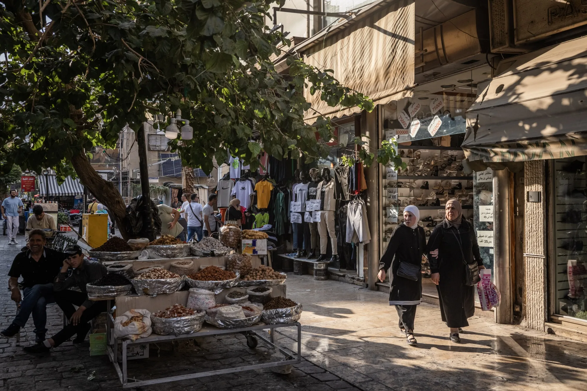 Shoppers pass stores and food stalls in Damascus.