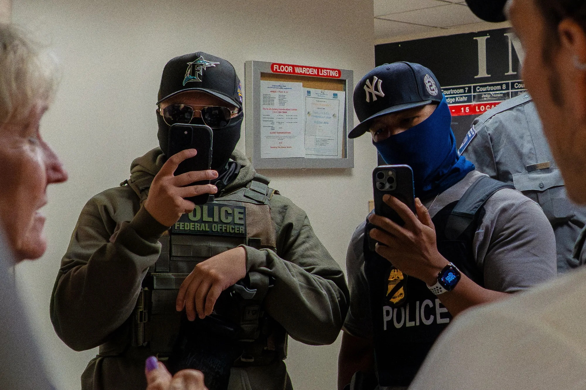 Two ICE agents use&nbsp;smartphones outside of&nbsp;immigration court&nbsp;in New York.