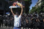 A person holds an image of the late Argentine football star Diego Maradona in front of riot police during a tribute to Maradona outside the Casa Rosada presidential palace in Buenos Aires, Argentina, in November 2020. 