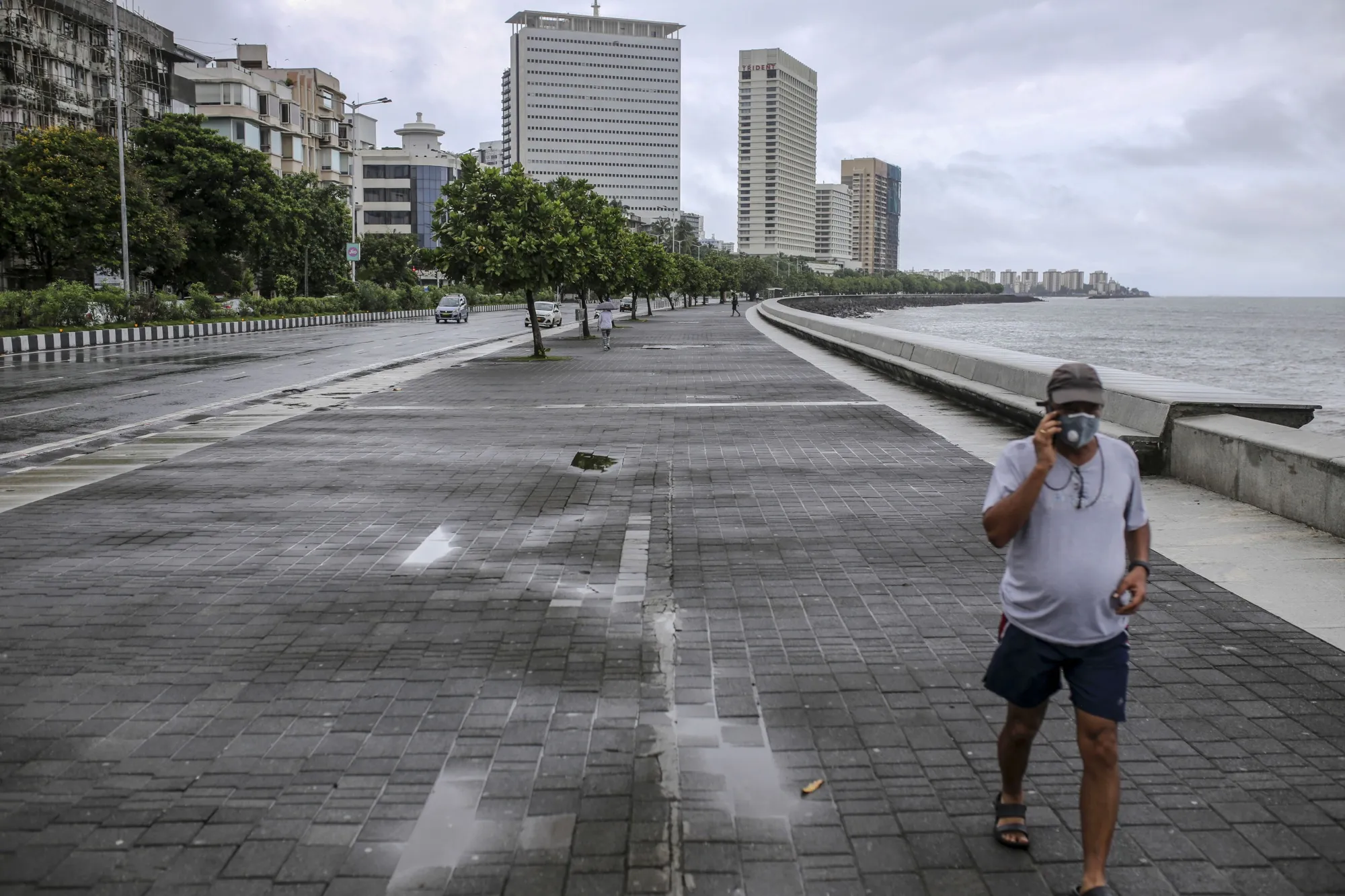A pedestrian wearing a protective mask walks along a deserted Marine Drive in Mumbai, July 14.