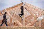 Workers install roof trusses on a home under construction in Vineyard, Utah.