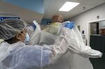 A nurse assists a doctor putting on protective gear before entering the Covid-19 intensive care unit (ICU) at the United Memorial Medical Center (UMMC) in Houston, Texas, U.S., on Monday, June 29, 2020.