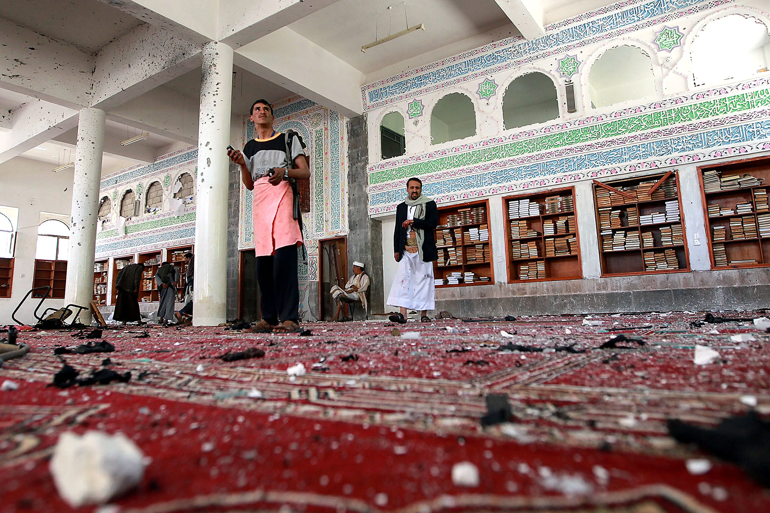 Yemeni armed men inspect the damage following a bomb explosion at the Badr mosque in southern Sanaa on March 20, 2015.
