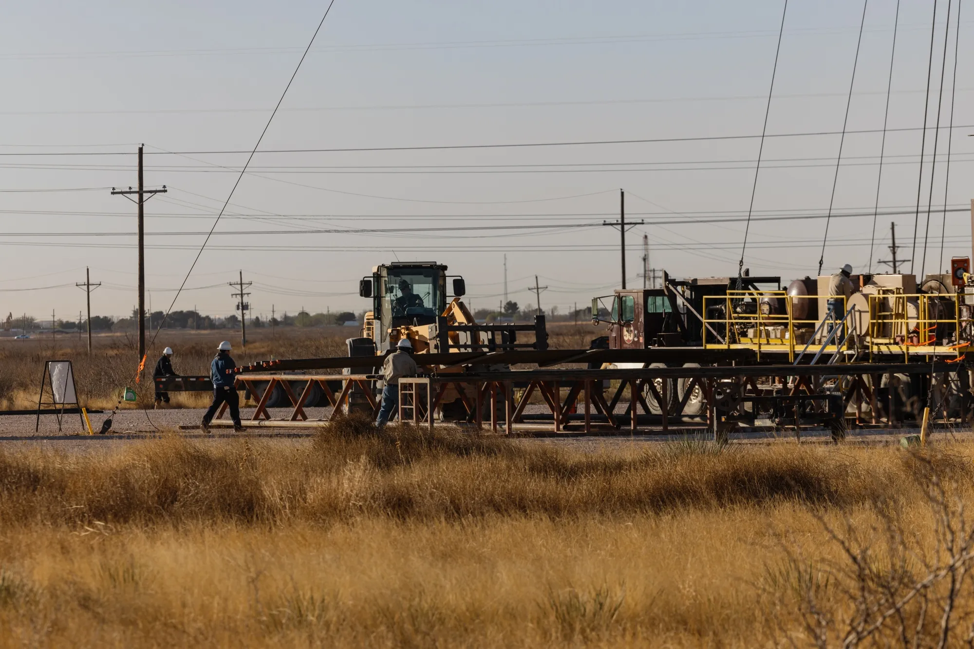 Oilfield workers construct a vertical drilling rig in Texas